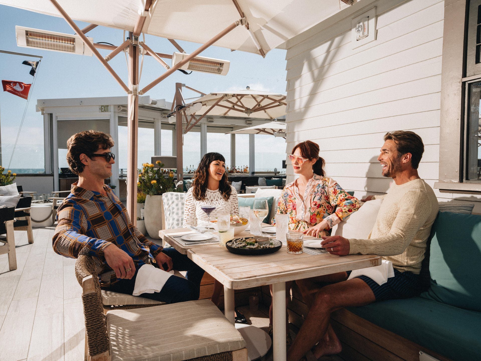 a group sitting around a table under an umbrella outdoors